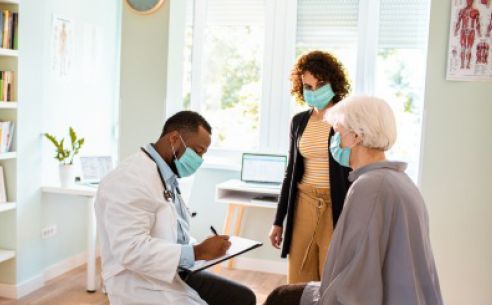 Elderly woman getting advice from a doctor as another woman looks on.
