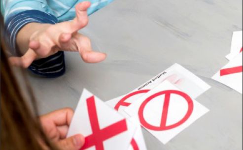 Man with hands affected by deformity reaching for cards with red