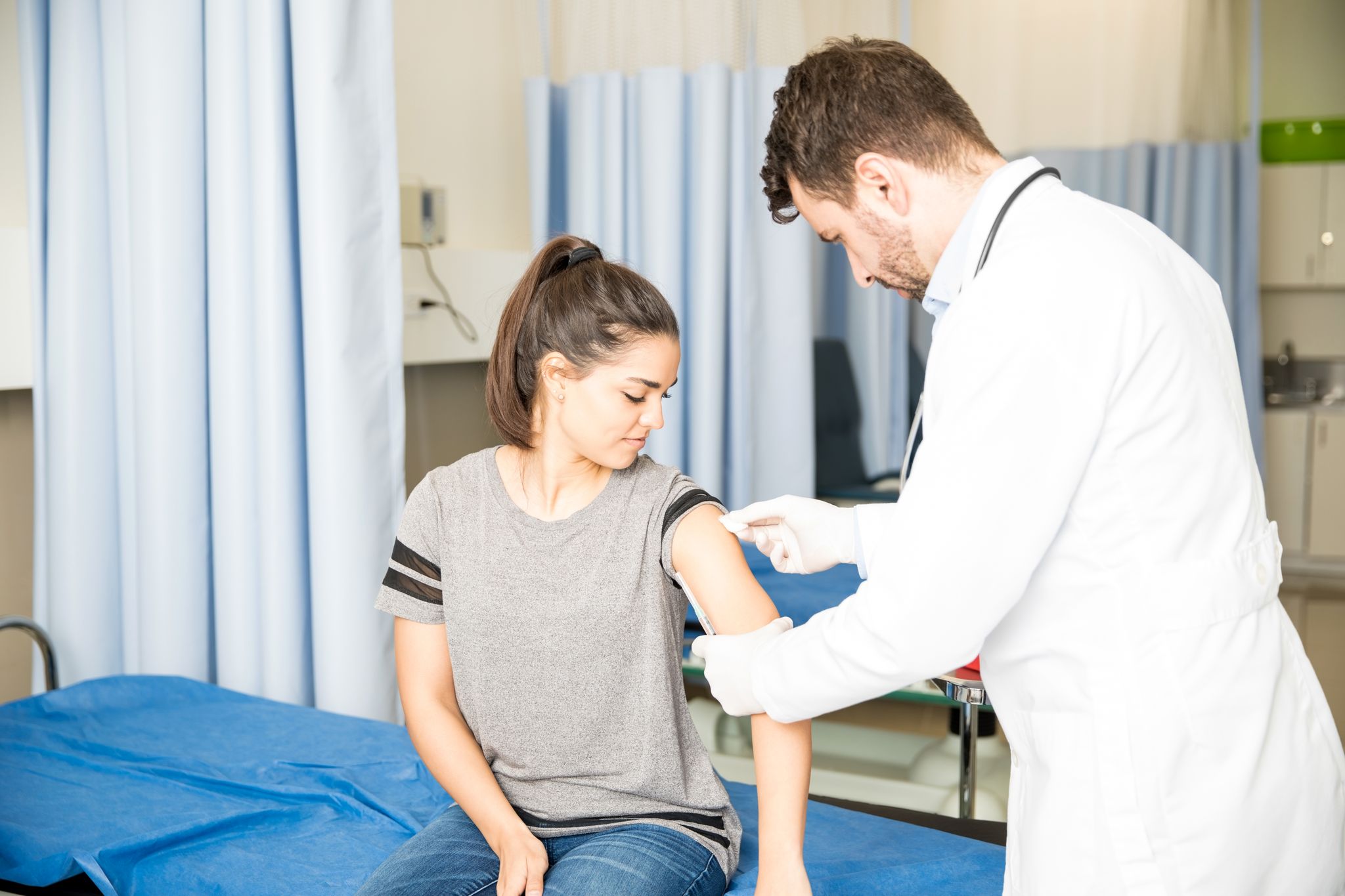 A young woman being prepared for an injection by a doctor.