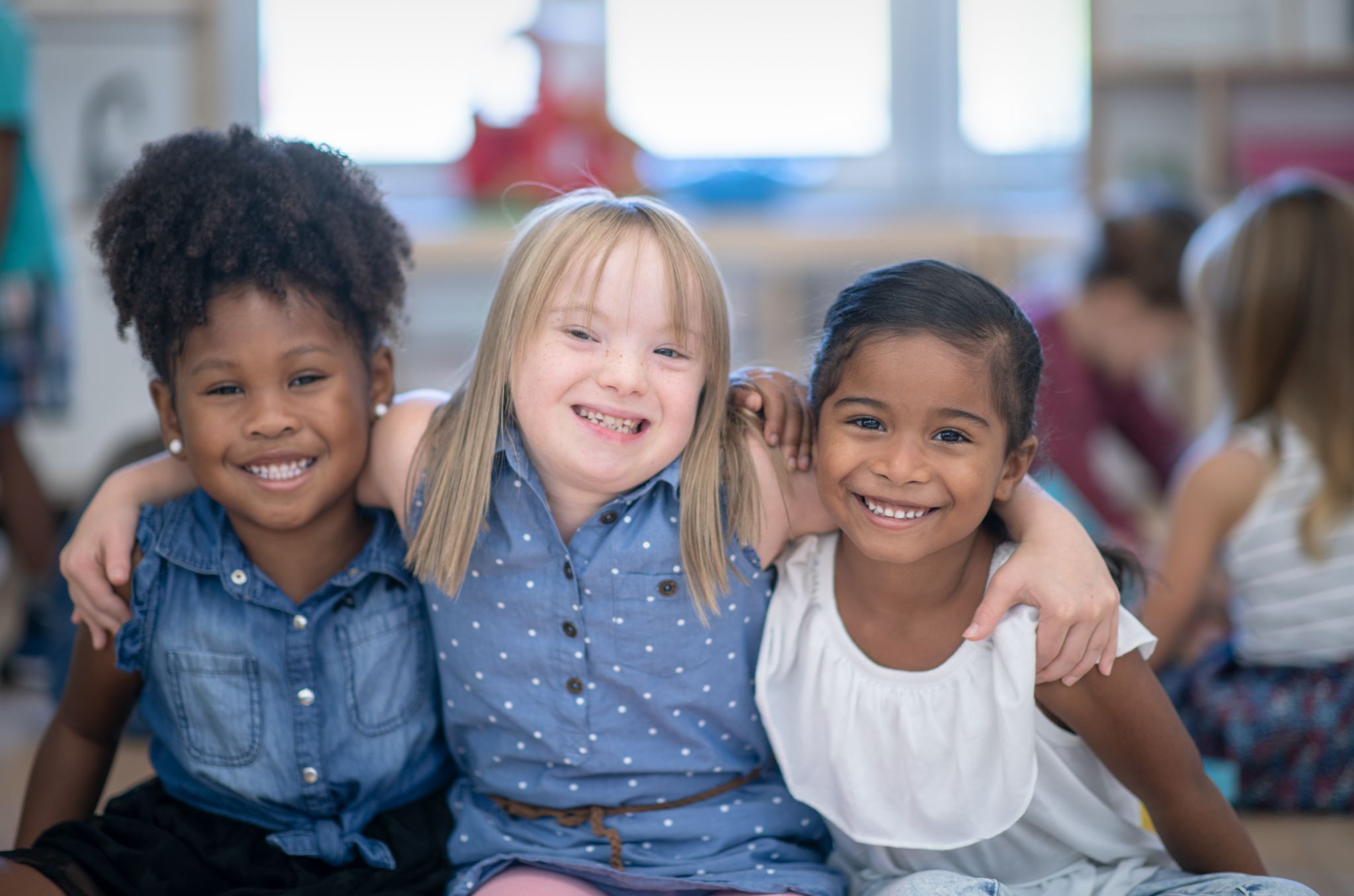 Three girls with their arms around each other and smiling.